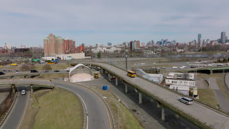 Tracking-of-yellow-school-bus-passing-on-long-elevated-exit-ramp-of-road-interchange-in-city.-Boston,-USA
