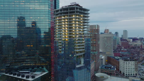 Slide-and-pan-footage-of-construction-new-tall-building.-Surrounding-skyscrapers-reflecting-other-buildings-in-glossy-glass-facade.-Boston,-USA