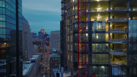 Imágenes-Aéreas-Ascendentes-A-Lo-Largo-De-La-Pared-Del-Nuevo-Edificio-De-Oficinas-Moderno-En-Construcción.-Centro-En-El-Crepúsculo.-Boston,-Estados-Unidos