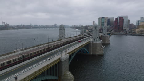Tracking-of-subway-red-line-train-passing-on-Longfellow-Bridge-over-wide-Charles-river-on-cloudy-day.-Boston,-USA