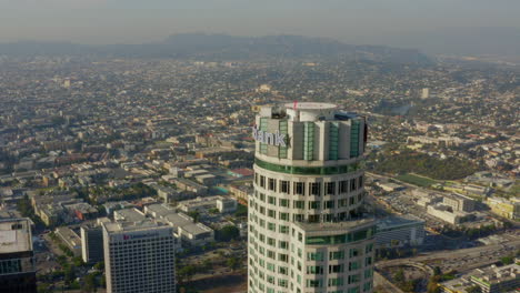 Antena:-Cerca-De-La-Parte-Superior-Del-Rascacielos-Del-Banco-Estadounidense,-Helipuerto-En-El-Centro-De-Los-ángeles,-California-Con-Hermosa-Luz-Del-Sol,-Cielo-Azul,