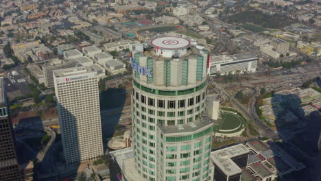 Plano-Medio-Del-Icónico-Edificio-De-Rascacielos-Famoso-En-El-Centro-De-Los-Ángeles,-El-Horizonte-De-California-A-La-Luz-Del-Cielo-Azul,-El-Establecimiento-De-La-Izquierda-Del-Tobogán-Aéreo