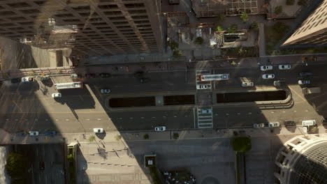 AERIAL:-Slow-lowering-birds-eye-View-flight-over-Downtown-Los-Angeles-California-Grand-Avenue-in-beautiful-Sunrise-Light-with-view-of-skyscraper-rooftops-and-car-traffic-passing