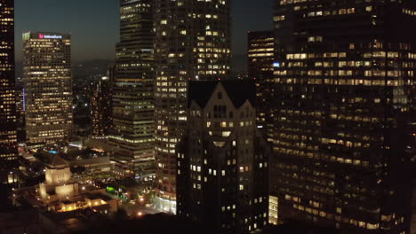 Malerische-Weite-Ansicht-Von-Wolkenkratzern-In-Der-Großstadt-Bei-Nacht-Mit-Beleuchteten-Beleuchteten-Gebäuden-In-Der-Skyline-Von-Los-Angeles,-Aufsteigende-Aufnahme-Der-Luftdrohne