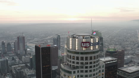 AERIAL:-Close-Up-of-US-Bank-Skyscraper-Top,-Helipad-in-Downtown-Los-Angeles,-California-at-beautiful-Sunset