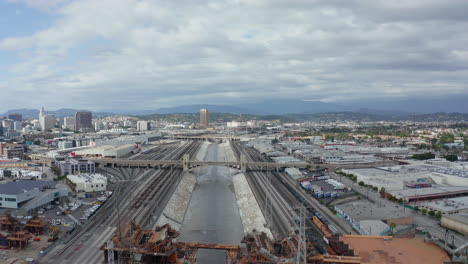 AERIAL:-View-over-Los-Angeles-River-Bridge-Being-Built-under-Construction-Site-with-Overcast-Cloudy-Sky