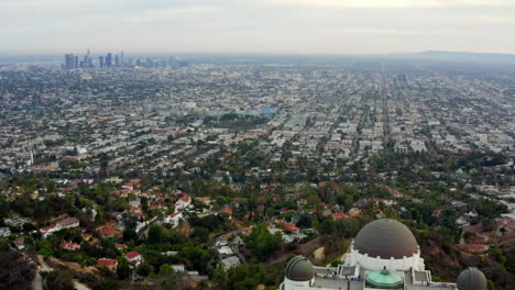 AERIAL:-Over-Griffith-Observatory-with-Los-Angeles,-California-Skyline-in-background-in-Daylight,Cloudy