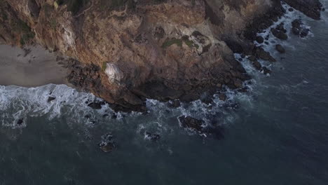 Blick-Nach-Unten-Auf-Die-Klippenküste-In-Kalifornien-Mit-Meereswellen,-Die-Auf-Felsen-Krachen,-Vogelperspektive-Aus-Der-Vogelperspektive