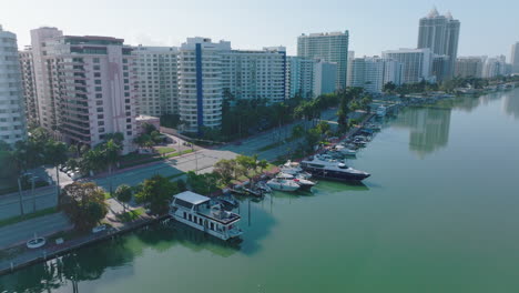 Yachts-moored-along-waterfront.-Aerial-view-of-creek-and-multilane-road-leading-along-tall-residential-buildings.-Miami,-USA