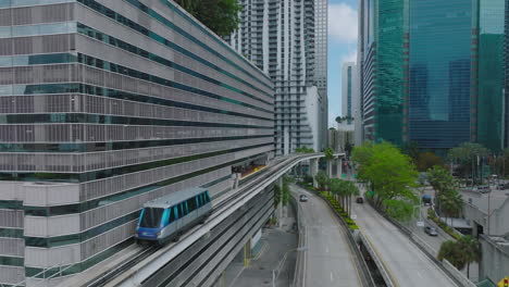 Futuristic-city-borough-with-modern-high-rise-buildings-and-automatic-passenger-transport-rail-vehicle.-Metromover-stopping-at-station.-Miami,-USA