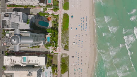 Fly-along-sea-coast.-Waves-washing-sand-coast.-Top-down-view-of-tropical-vacation-resort.-Miami,-USA