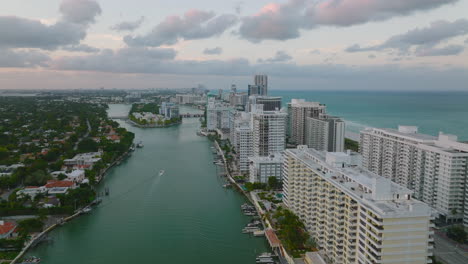 Aerial-view-of-large-apartment-buildings-along-sea-coast-at-sunset-time.-Low-traffic-on-trunk-road-in-city.-Miami,-USA