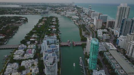 High-angle-view-of-motorboat-passing-under-lifted-road-bridge.-Vehicles-waiting-in-queues-on-road.-Fly-above-urban-neighbourhood.-Miami,-USA