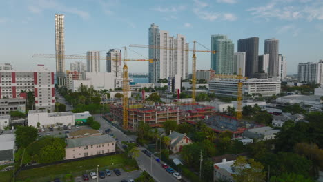 Construction-site-in-city.-Yellow-tall-cranes-and-modern-high-rise-buildings-in-background.-Miami,-USA