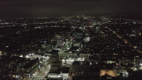 AERIAL:-Over-Dark-Hollywood-Los-Angeles-at-Night-with-view-on-Skyline-and-City-Lights