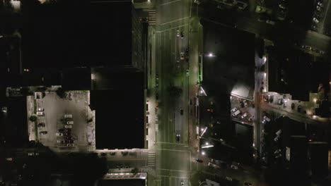 AERIAL:-Overhead-View-on-Wilshire-Boulevard-Street-in-Hollywood-Los-Angeles-at-Night-with-Glowing-Streets-and-City-Car-Traffic-Lights