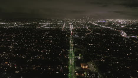 Antena:-Vista-De-Los-Ángeles-Por-La-Noche-Con-Las-Calles-Resplandecientes-Del-Bulevar-Wilshire-Y-Los-Semáforos-De-Los-Automóviles-De-La-Ciudad