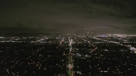 AERIAL:-View-over-Los-Angeles-at-Night-with-Wilshire-Boulevard-Glowing-Streets-and-City-Car-Traffic-Lights