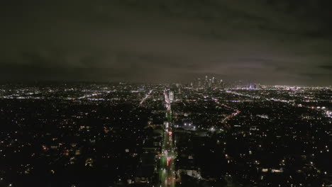 Luftbild:-Blick-über-Los-Angeles-Bei-Nacht-Mit-Wilshire-Boulevard-Leuchtenden-Straßen-Und-Stadtautoampeln