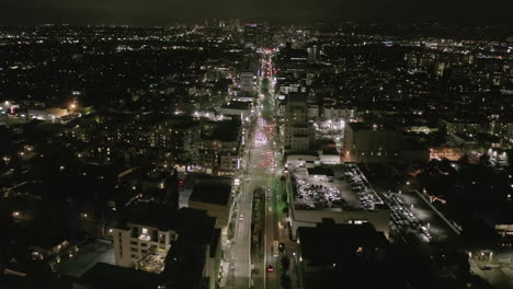 AERIAL:-Flight-over-Wilshire-Boulevard-Street-in-Hollywood-Los-Angeles-at-Night-with-View-on-Streets-and-City-Car-Traffic-Lights