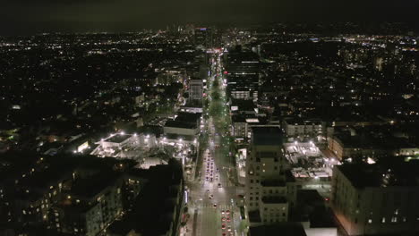 AERIAL:-Flight-over-Wilshire-Boulevard-Street-in-Hollywood-Los-Angeles-at-Night-with-View-on-Streets-and-City-Car-Traffic-Lights