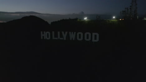 AERIAL:-Flight-over-Hollywood-Sign-,-Hollywood-Hills-at-Night-with-view-on-Valley-,-Burbank-and-City-Lights