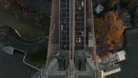 Aerial-birds-eye-overhead-top-down-panning-view-of-vehicles-driving-on-Brooklyn-bridge-over-river.-Heavy-traffic-on-road.-Manhattan,-New-York-City,-USA
