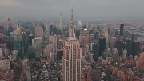 Antenne:-Nahaufnahme-Des-Empire-State-Building-Mit-Midtown-Manhattan,-Times-Square-Im-Hintergrund-Bei-Sonnenaufgang,-Sonnenuntergang