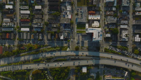 Busy-multilane-highway-and-buildings-in-residential-neighbourhoods-around.-Top-down-footage-at-golden-hour.-Miami,-USA