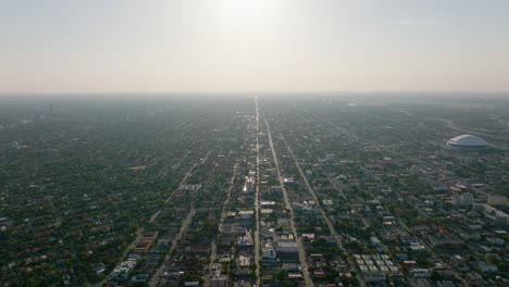 Aerial-panoramic-footage-of-large-area-covered-with-low-residential-houses-surrounded-with-trees-and-greenery.-View-against-setting-sun.-Miami,-USA