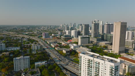 Aerial-panoramic-view-of-urban-borough.-Tilt-down-on-busy-multilane-highway-and-bright-low-sun-casting-long-shadows.-Miami,-USA