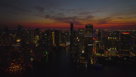 Slide-and-pan-aerial-footage-of-modern-high-rise-apartment-buildings-around-river-estuary.-Skyscraper-silhouettes-against-romantic-twilight-sky.-Miami,-USA