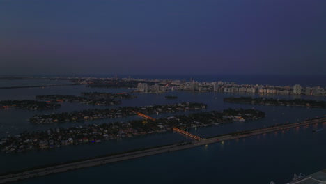 Forwards-fly-above-islands-in-Biscayne-Bay-after-sunset.-Busy-MacArthur-Causeway-in-foreground.-Miami,-USA