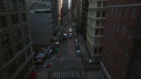 Forwards-fly-above-street,-vehicles-driving-on-one-way-road-between-high-rise-downtown-buildings.-Manhattan,-New-York-City,-USA