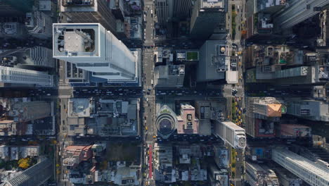 Aerial-birds-eye-overhead-top-down-view-of-vehicles-driving-in-wide-streets-at-passing-through-intersections-in-city-divided-to-regular-blocks-of-buildings.-Manhattan,-New-York-City,-USA