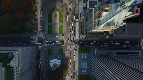 Aerial-birds-eye-overhead-top-down-descending-footage-of-traffic-in-streets-and-crossroads-around-Central-park.-Pulitzer-and-Grand-Army-Plaza-from-height.-Manhattan,-New-York-City,-USA