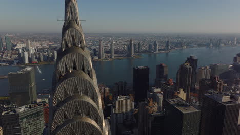 Fliegen-Sie-Um-Die-Spitze-Des-Legendären-Chrysler-Building-Herum.-Aufschlussreichen-Blick-Auf-Den-Breiten-East-River-Und-Die-Stadtbezirke-Am-Gegenüberliegenden-Ufer.-Manhattan,-New-York-City,-Vereinigte-Staaten