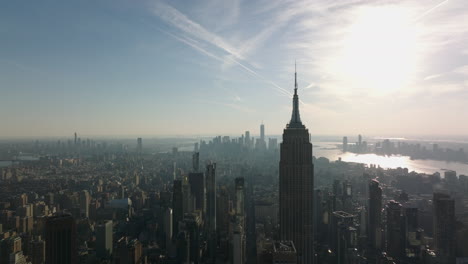 Vorwärts-Fliegen-über-Der-Stadt.-Silhouette-Des-Ikonischen-Empire-State-Building-Gegen-Die-Sonne.-Dunstige-Sicht-Auf-Das-Stadtbild.-Manhattan,-New-York-City,-Vereinigte-Staaten