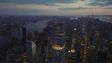 Evening-aerial-panoramic-footage-of-midtown-with-tall-skyscrapers-surrounded-by-water-surface.-Colourful-twilight-sky.-Manhattan,-New-York-City,-USA