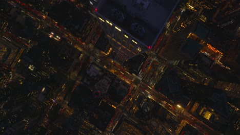Aerial-birds-eye-overhead-top-down-footage-of-downtown-at-night.-Fly-above-tall-modern-apartment-skyscraper.-Manhattan,-New-York-City,-USA