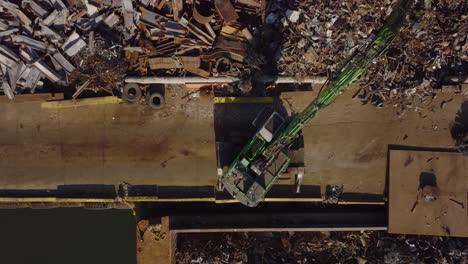 Aerial-birds-eye-overhead-top-down-footage-of-loader-grabbing-metal-scrap-and-loading-it-to-barge.-Recycle-and-ecology-concept.-New-York-City,-USA