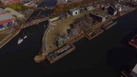 Aerial-descending-footage-of-loading-scrap-to-barge.-Recycling-facility-on-Newtown-Creek-waterfront.-New-York-City,-USA