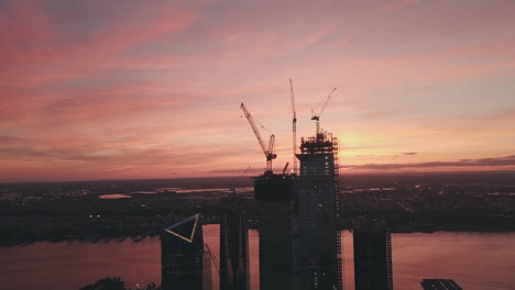 AERIAL:-Manhattan,-New-York-City-High-Rise-Construction-Site-Crane-in-Red-Dawn-Sunset-Light