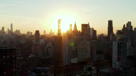 Fly-above-town.-Silhouettes-of-tall-office-towers-against-setting-sun.-Manhattan,-New-York-City,-USA