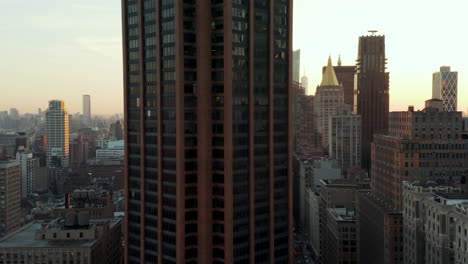 Fly-around-tall-building-in-city.-Revealing-skyline-with-downtown-skyscrapers-against-sunset.-Manhattan,-New-York-City,-USA