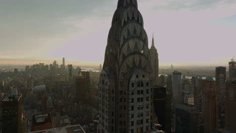 Top-section-of-Chrysler-Building-with-crown-decoration-against-setting-sun.-Revealing-tall-Empire-State-Building.-Manhattan,-New-York-City,-USA