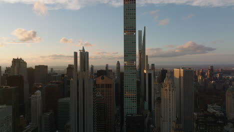 Fly-above-city-at-sunset.-Tall-apartment-and-office-buildings-lit-by-bright-sunshine.-Manhattan,-New-York-City,-USA