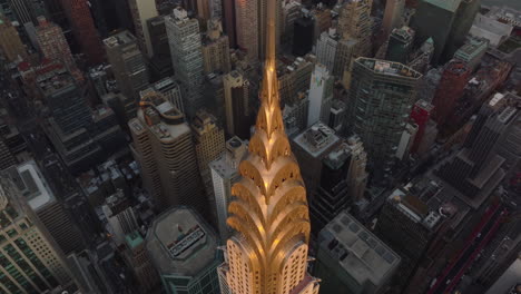 Vuela-Sobre-La-Corona-Decorativa-Y-La-Aguja-Alta-En-La-Parte-Superior-Del-Edificio-Chrysler-Iluminado-Por-La-Luz-Dorada-Del-Atardecer.-Manhattan,-Ciudad-De-Nueva-York,-Estados-Unidos