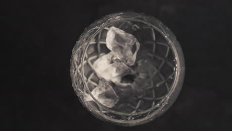 Ice-cubes-falls-empty-glass-closeup.-Refreshing-drink-preparation-concept