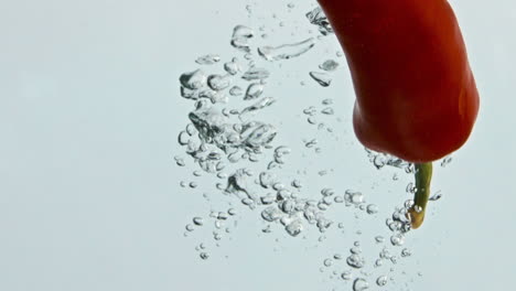 Chili-pepper-falling-water-in-light-background-closeup.-Spicy-red-vegetable